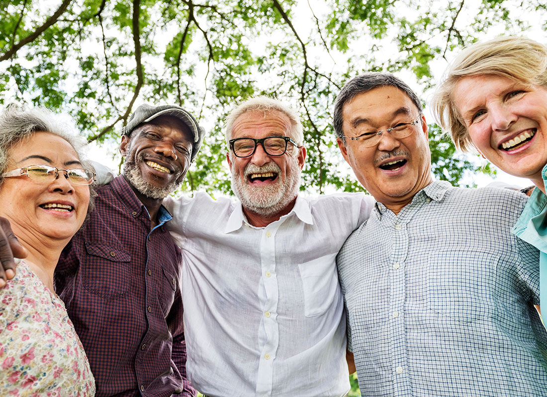 Review Us - Closeup Portrait of a Cheerful Diverse Group of Seniors Standing Together as a Group Outside in the Park on a Sunny Day